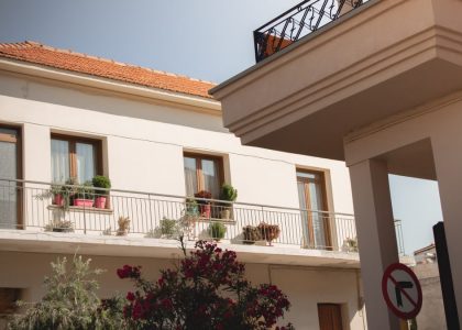 Traditional Greek house facade with potted plants and balcony details.